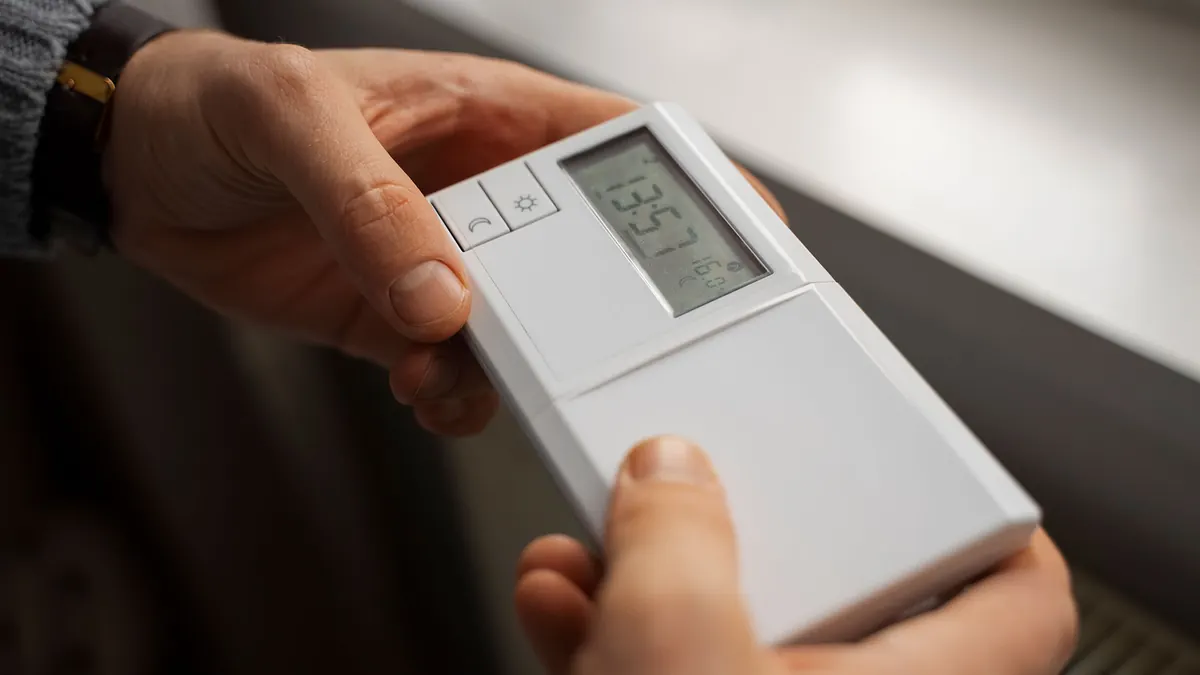 Ruke drže digitalni sobni termostat s LCD zaslonom